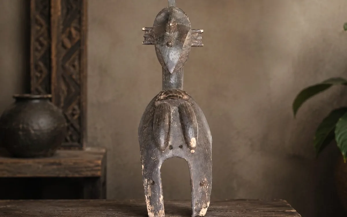 Petite statuette en bois sombre dressée sur une table ancienne