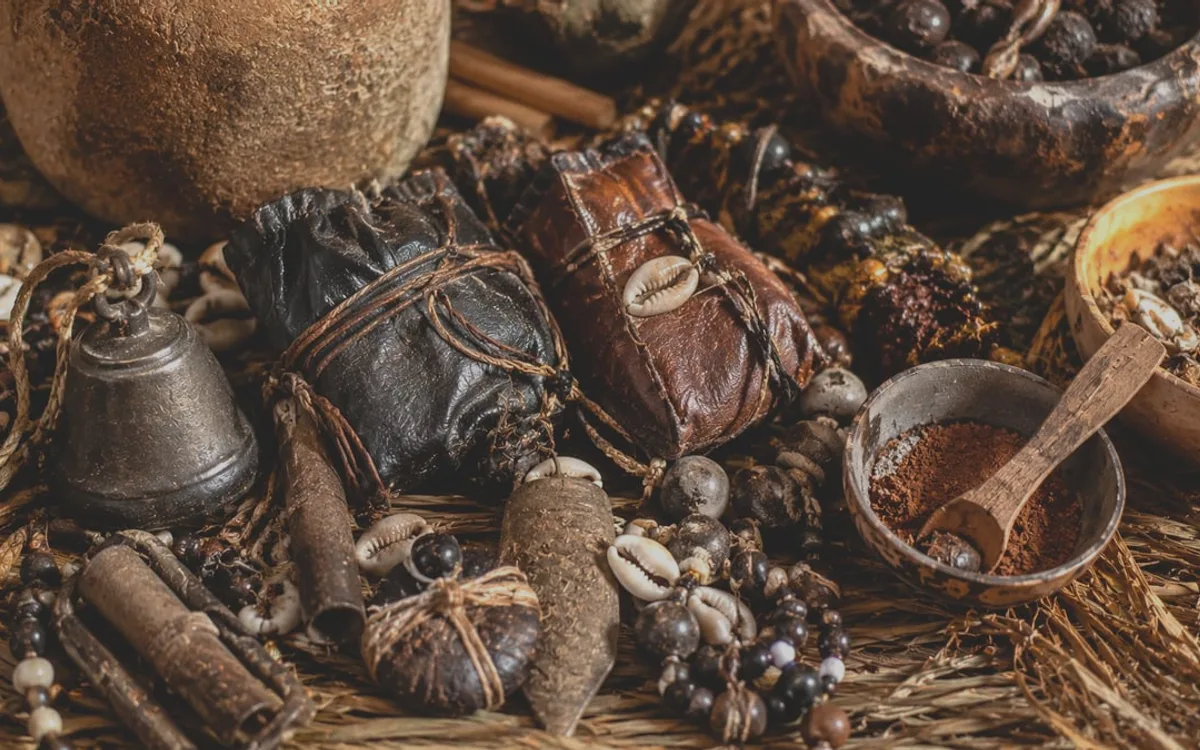 Amulette en cuir posée sur une natte tressée, entourée de cauris et de perles